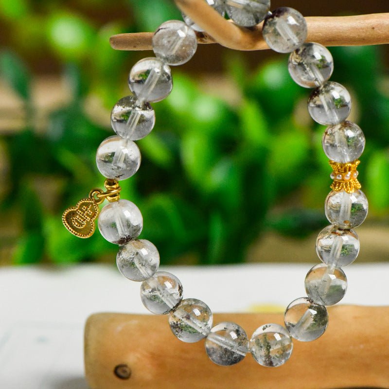 Green Phantom Quartz crystal bracelet for prosperity, displayed against a lush green background.